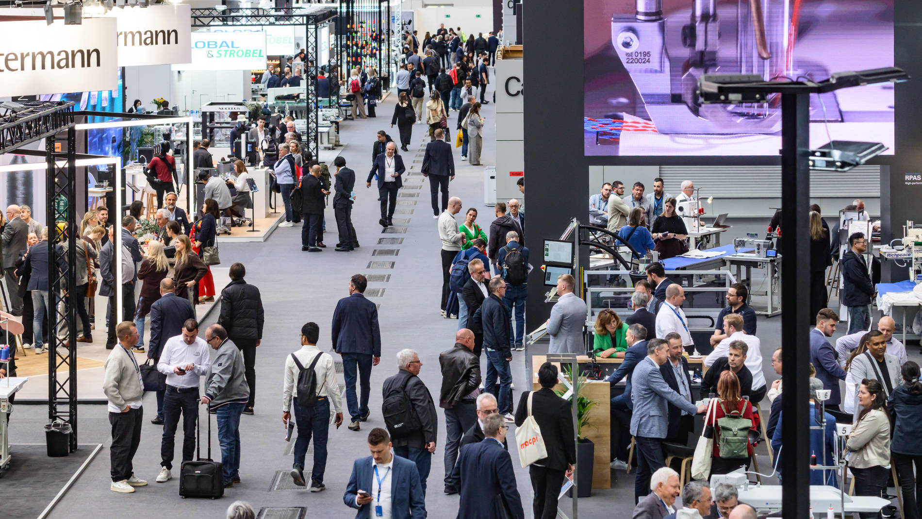 Many people walking through busy exhibition hall of Texprocess